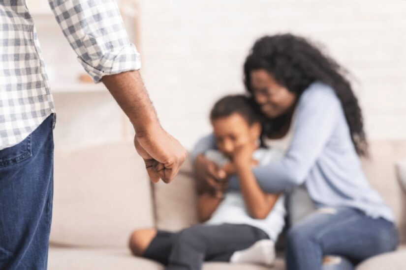 Man Holding His Fist Tight And A Crying Woman With A Child In The Background