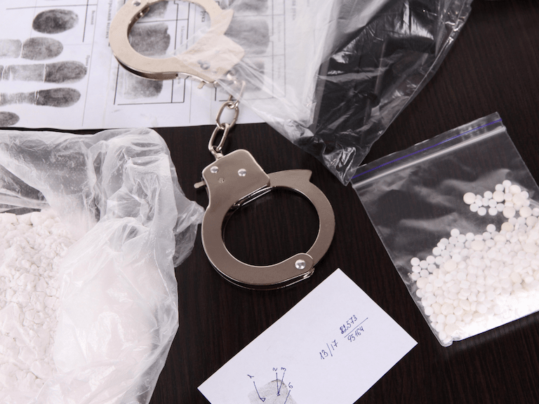 manufacture delivery of a controlled substance texas Handcuffs Next To Sealed Drugs
