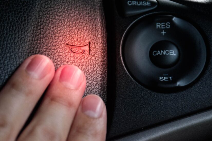 Hand pressing the horn on the steering wheel of a car