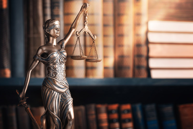 Lady Justice holding scales in front of law library
