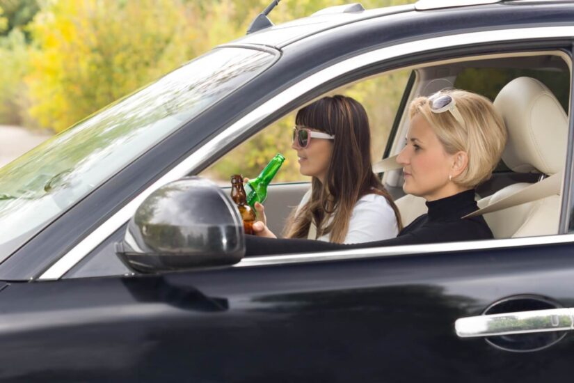 Enjoying alcohol while driving Two woman enjoying alcohol while driving