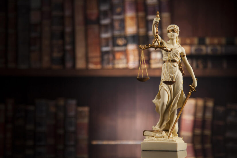 Statue of Justia in front of bookshelf