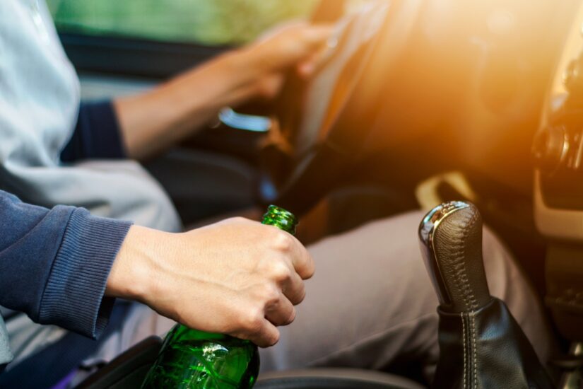 Driver holding beer bottle while driving