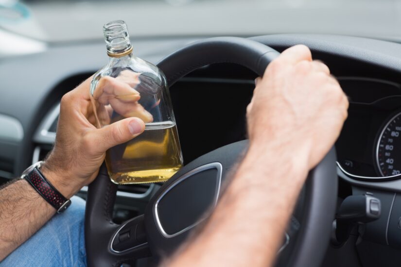 Drunk driver Driver holding alcohol bottle while driving